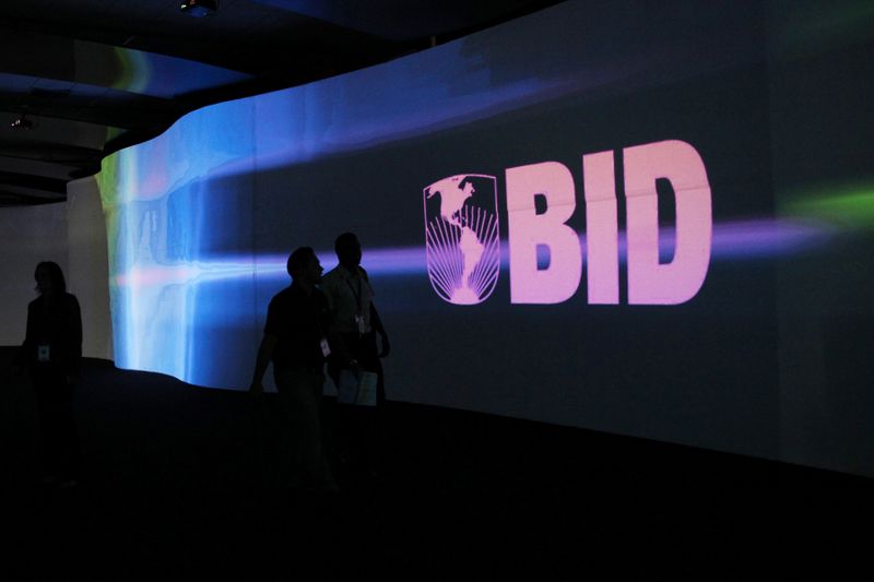 FILE PHOTO: Visitors walk past a screen with the logo of Banco Interamericano de Desarrollo at the Atlapa Convention Center in Panama City