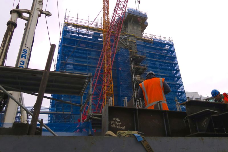 FILE PHOTO - Construction workers unload equipment at a building site for a residential apartment block in central Wellington, New Zealand