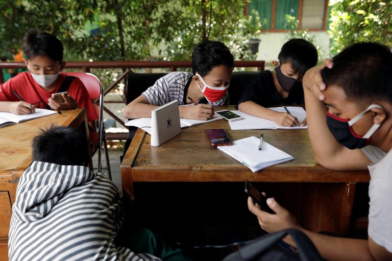 Dimas Anwar Saputra studies with other students at a local district office in Jakarta