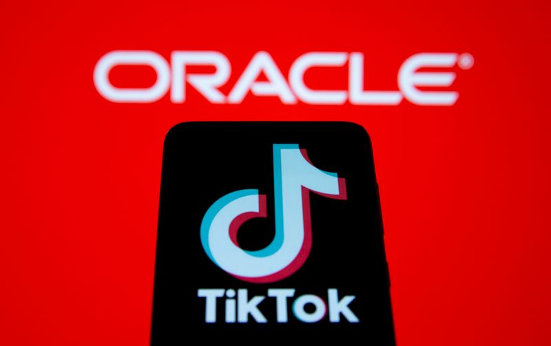 Smartphone with Tik Tok logo is seen in front of displayed Oracle logo in this illustration