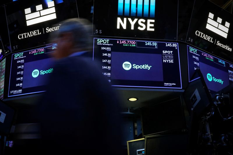 A trader passes by screens showing Spotify on the floor at the NYSE in New York