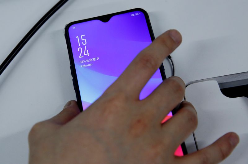 FILE PHOTO: A staff holds a smart phone which being tested for Rakuten's under-construction mobile network at its network facility in Tokyo