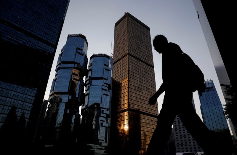 FILE PHOTO: A man walks past buildings at a business district in Hong Kong