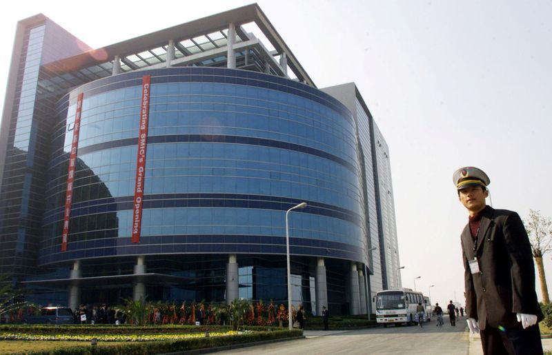 FILE PHOTO: A security officer stands outside a building of SMIC during its grand opening in Shanghai November 22, 2001.