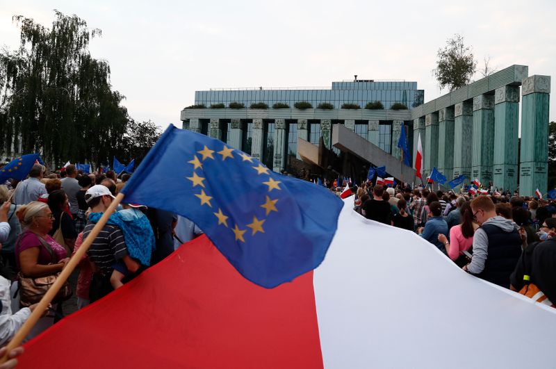 People wave EU and Polish flags during a protest against supreme court legislation in Warsaw