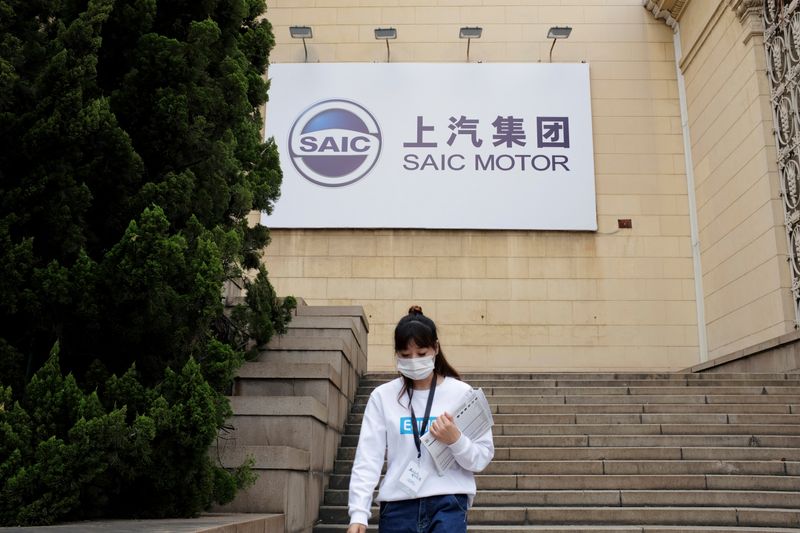 Woman wearing a face mask following the coronavirus disease (COVID-19) outbreak walks by a SAIC Motor logo at a sales event in Shanghai