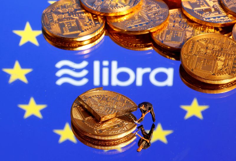 FILE PHOTO: A small toy figure is seen on representations of the virtual currency on a displayed European Union flag and the Facebook Libra logo in this illustration picture