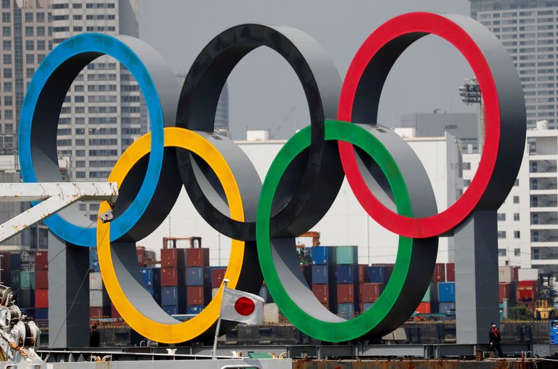 FILE PHOTO: The giant Olympic rings, which are being temporarily removed for maintenance, are seen behind Japan's national flag, at the waterfront area at Odaiba Marine Park in Tokyo