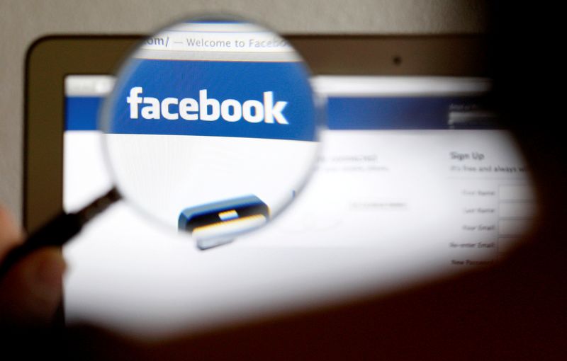 FILE PHOTO: In this photo illustration, a Facebook logo on a computer screen is seen through a magnifying glass held by a woman in Bern