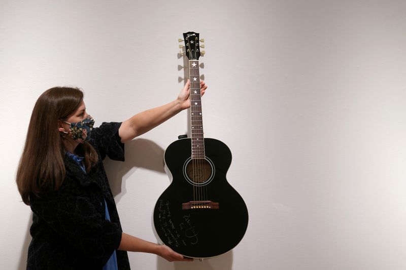 An employee of Christie's auction house holds a guitar used by singer Taylor Swift in New York