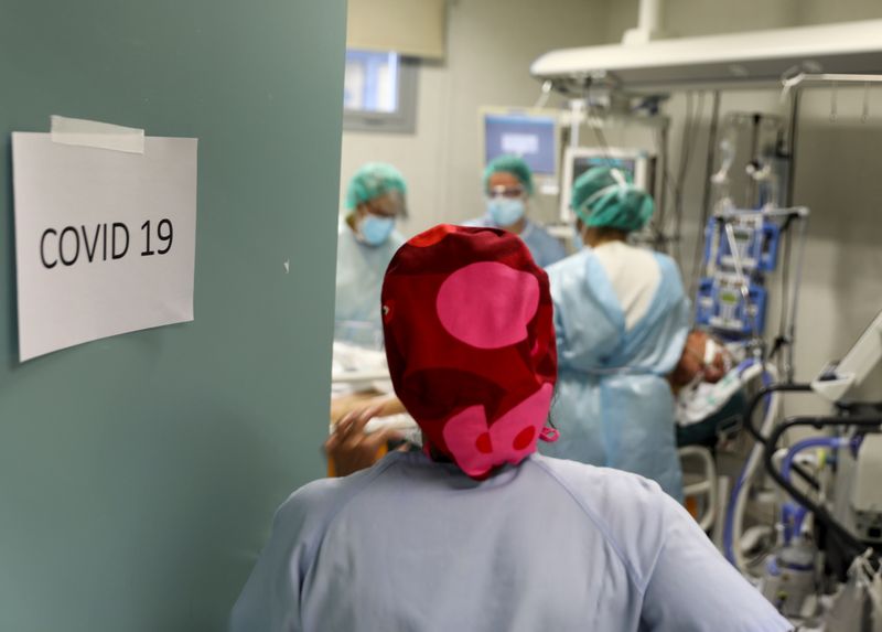 Medical workers take care of a patient infected with COVID-19 at the intensive care unit (ICU) of the Infanta Sofia University hospital in Spain