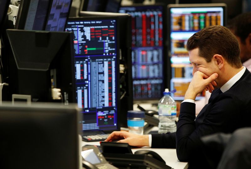 Traders work at their desks whilst screens show market data at CMC Markets in London