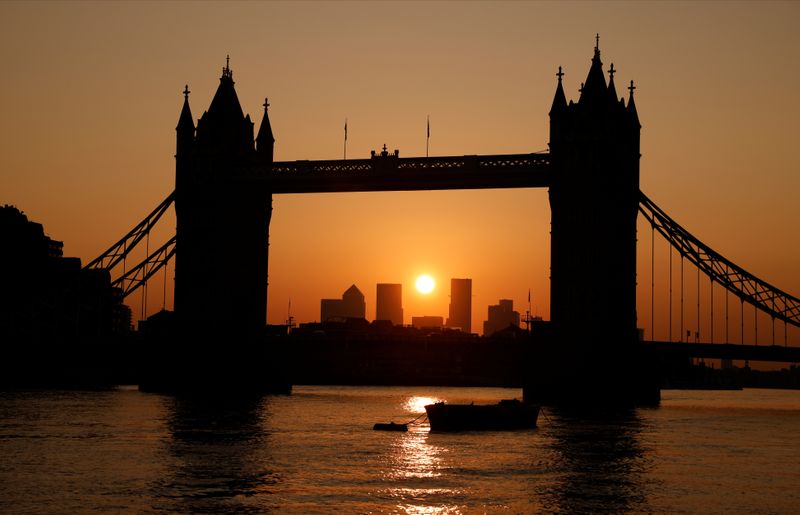 Tower Bridge with the Canary Wharf financial district in the background are seen at sunrise in London