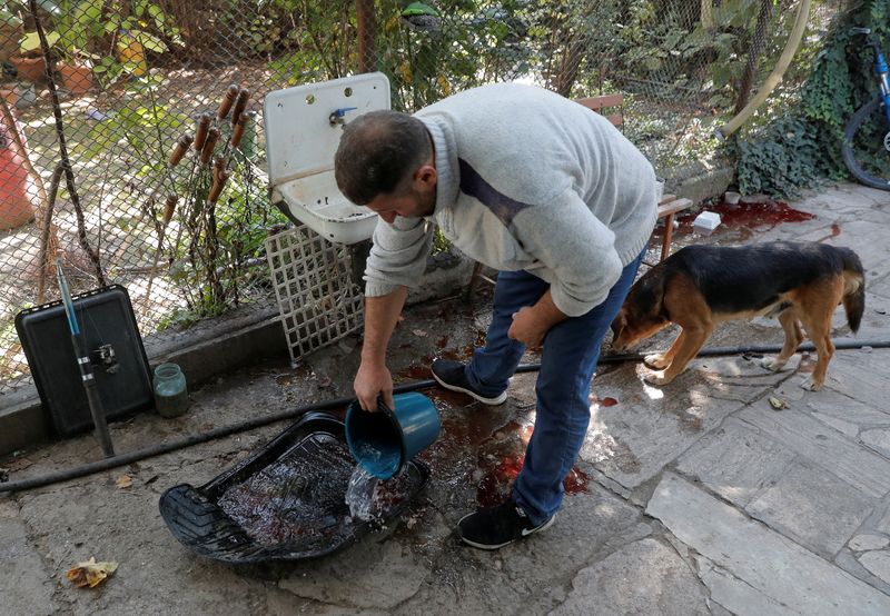 A man washes blood out of a mat of a car, which according to local residents transported people wounded by recent shelling, during a military conflict over the breakaway region of Nagorno-Karabakh, in the settlement of Karmir Shuka
