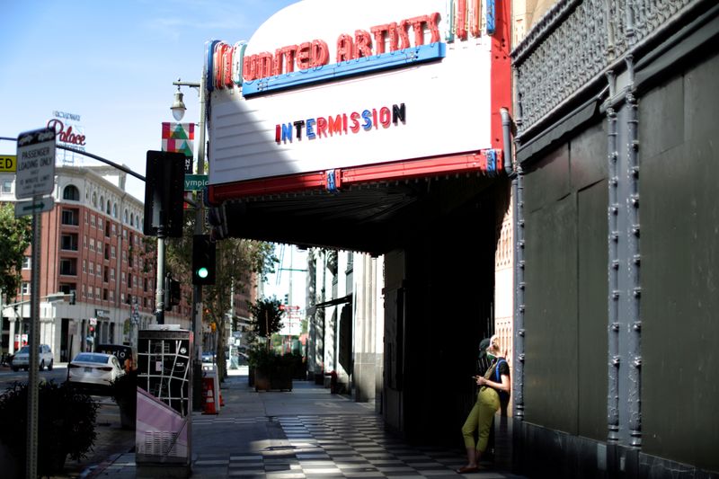 FILE PHOTO: A woman stands under a cinema entrance, as the global outbreak of the coronavirus disease (COVID-19) continues, in Los Angeles