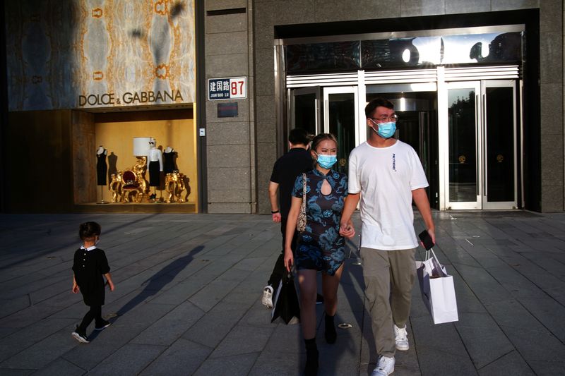 FILE PHOTO: People wearing face masks following the COVID-19 outbreak walk out of a shopping mall in Beijing