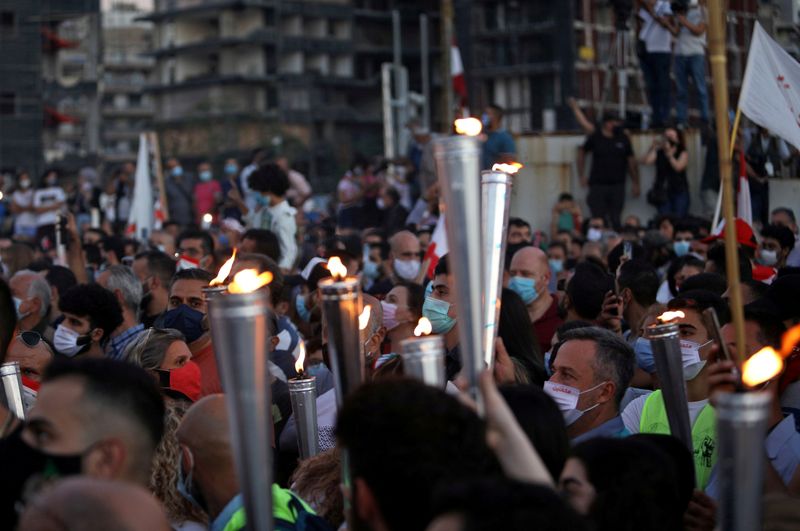 FILE PHOTO: People carry torches during a demonstration marking one year since the start of nation-wide protests near Beirut's port