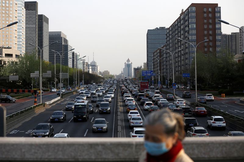 A woman wearing a face mask walks on a bridge as cars are seen in a traffic jam during evening rush hour in Beijing, as the country is hit by an outbreak of the novel coronavirus disease (COVID-19)