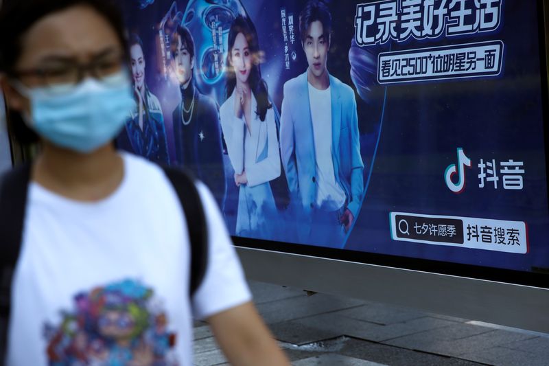 Pedestrian wearing a face mask following the coronavirus disease (COVID-19) outbreak walks past an advertisement of TikTok (Douyin) at a bus stop in Beijing