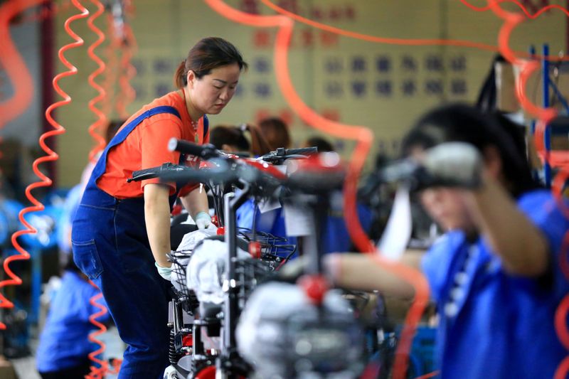 FILE PHOTO: Woman work on manufacturing electric bicycles at a factory in Huaian, Jiangsu