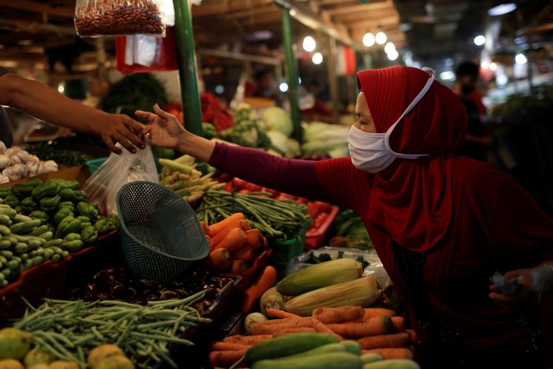 A woman wearing a protective mask shops for vegetables at a traditional market, as the coronavirus disease (COVID-19) outbreak continues, in Jakarta