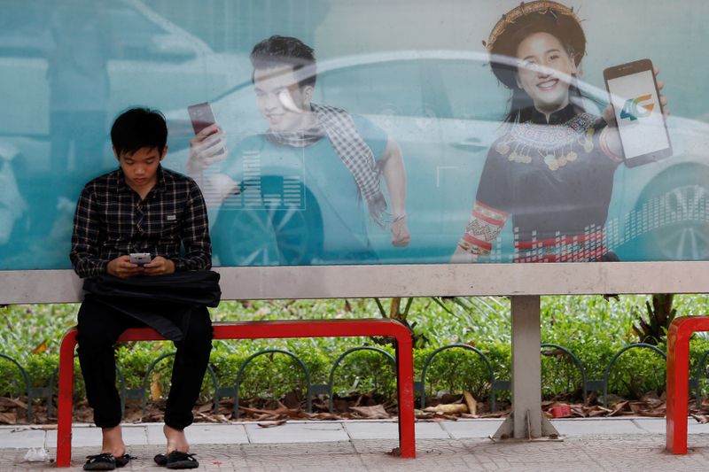 An internet user browses the Internet in front of an advertising billboard for 4G connection service at a bus stop in Hanoi