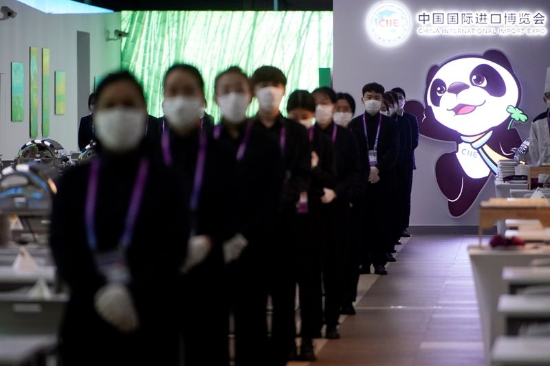 Staff members wearing face masks are seen at the third China International Import Expo (CIIE) in Shanghai
