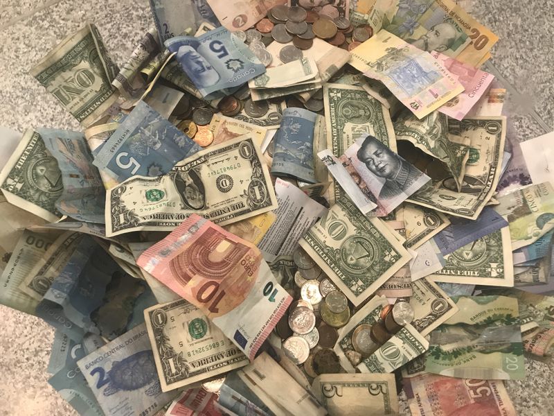 FILE PHOTO: U.S. dollars and other world currencies lie in a charity receptacle at Pearson international airport in Toronto