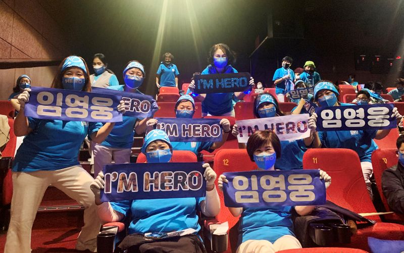 Fans of South Korean singer Lim Young-woong pose for photographs with banners bearing his name, before watching a movie featuring