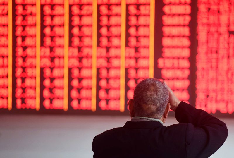 Man sits in front of an electronic board showing stock information at a brokerage house in Hangzhou