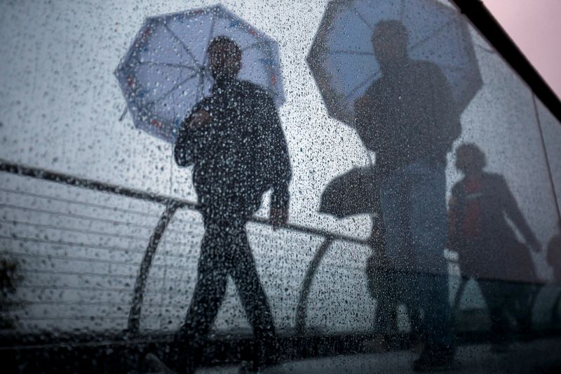 FILE PHOTO: Pedestrians walk across the Millennium Footbridge during rainy weather in London