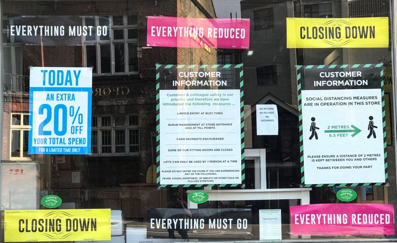 FILE PHOTO: Closing down, reductions and social distancing posters are seen in a closed retail shop window in London