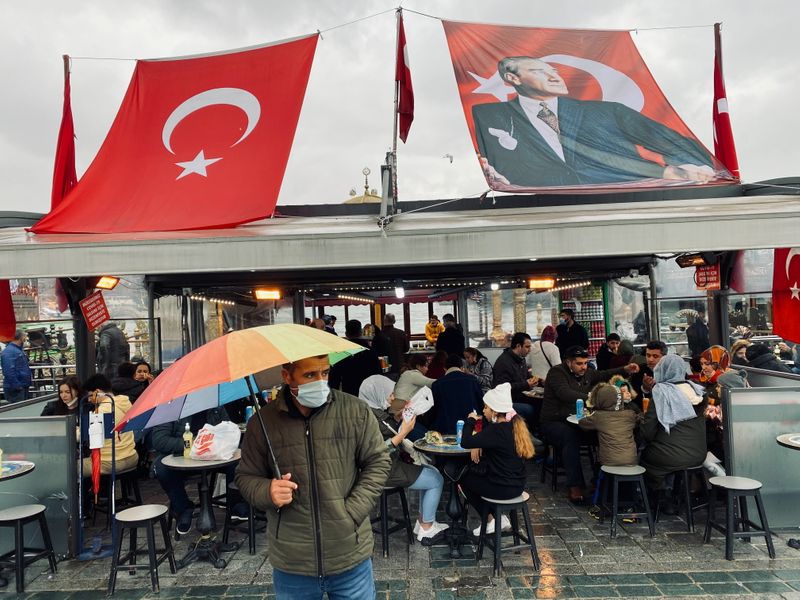 Man wearing a protective mask stands in front of a fish and bread restaurant in Istanbul