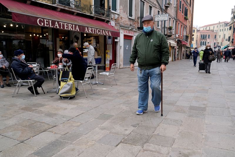 FILE PHOTO: People wearing masks walk on a street, as the number of people infected by the coronavirus disease (COVID-19) continues to rise, in Venice