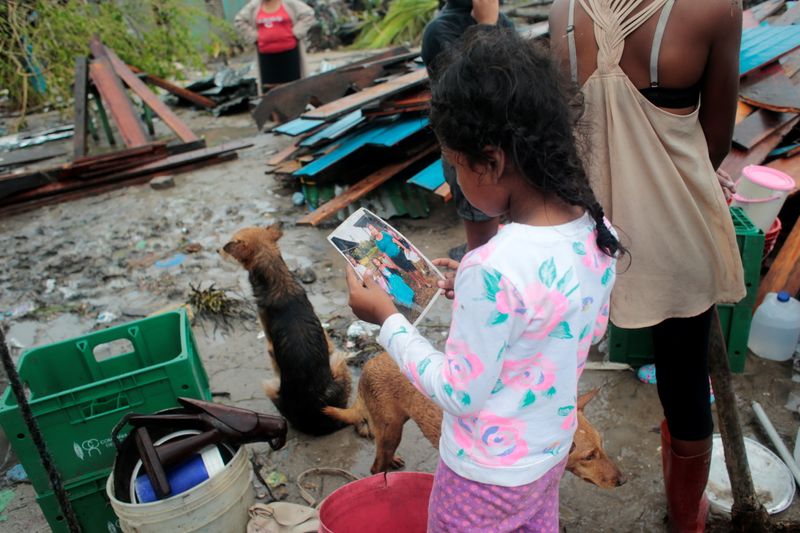 A girl looks at a family photo recovered from the debris of her house destroyed after the passing of Hurricane Iota, in Puerto Cabezas