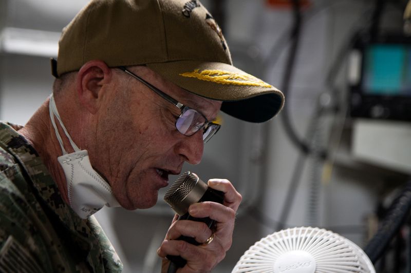 U.S. Navy sailors assigned to the aircraft carrier USS Theodore Roosevelt and embarked staff listen to Vice Admiral William Merz in Guam