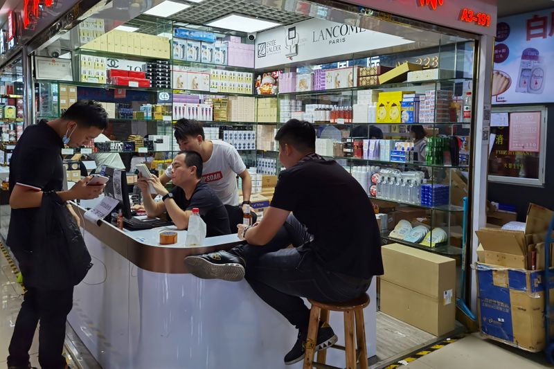 Cosmetics sellers check an order with a customer at the Mingtong Digital City market in Shenzhen's Huaqiangbei area