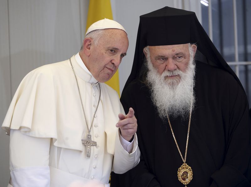 FILE PHOTO: Pope Francis gestures next to Archbishop Ieronymos II on the Greek Island of Lesbos