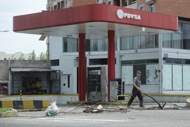 FILE PHOTO: A man walks past a closed gas station of the state oil company PDVSA in San Cristobal