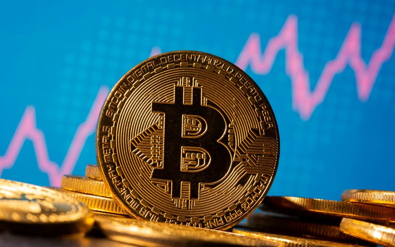 A representation of virtual currency Bitcoin is seen in front of a stock graph