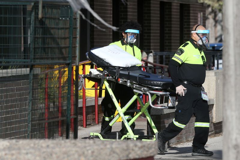 Employees of a stretcher service wear personal protective gear as they return a resident to Parkview Place personal care home, which is experiencing an outbreak of the coronavirus disease (COVID-19), in Winnipeg