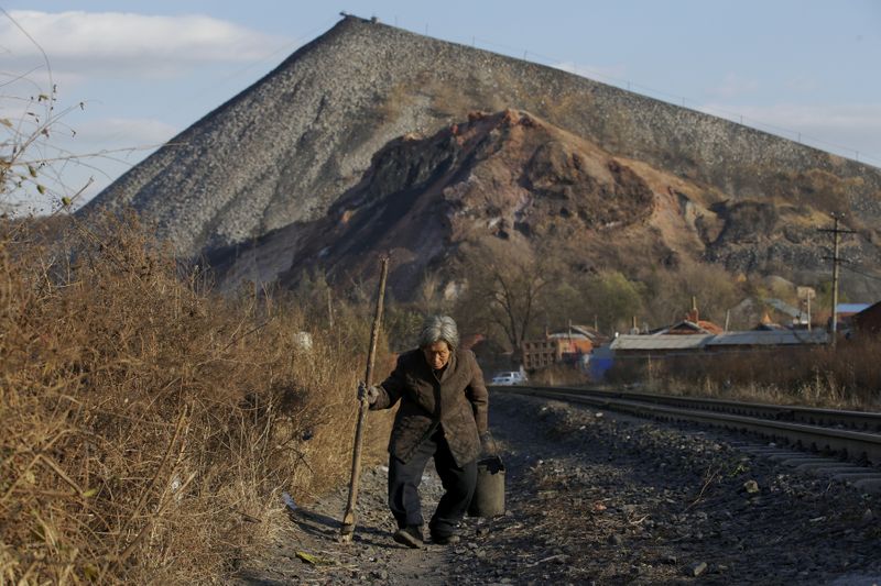 FILE PHOTO: An elderly villager walks along a railway which is used to transfer coal outside Shuanghe coal mine on the outskirts of Jixi in China