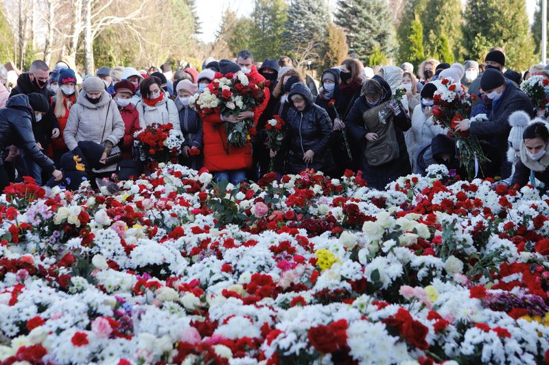 People lay flowers during a funeral of anti-government protester Roman Bondarenko in Minsk