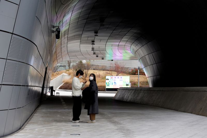 A couple wearing masks stand at a street amid the coronavirus disease (COVID-19) pandemic in Seoul