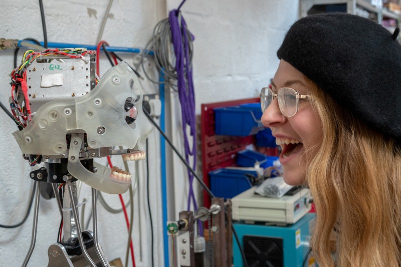 A woman interacts with Ai-Da, a humanoid robot capable of drawing people from life using her bionic eyes and hand, at the offices of robotics company Engineered Arts, in Falmouth