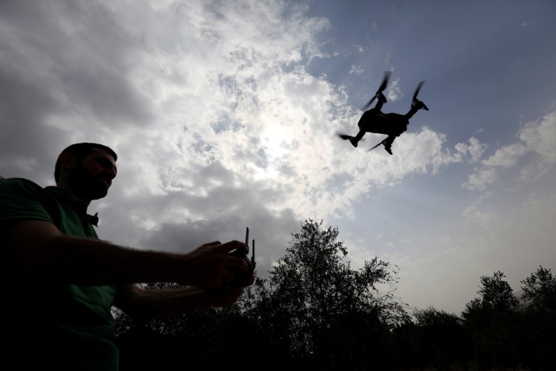 A man operates a drone over olive trees in Nabatieh