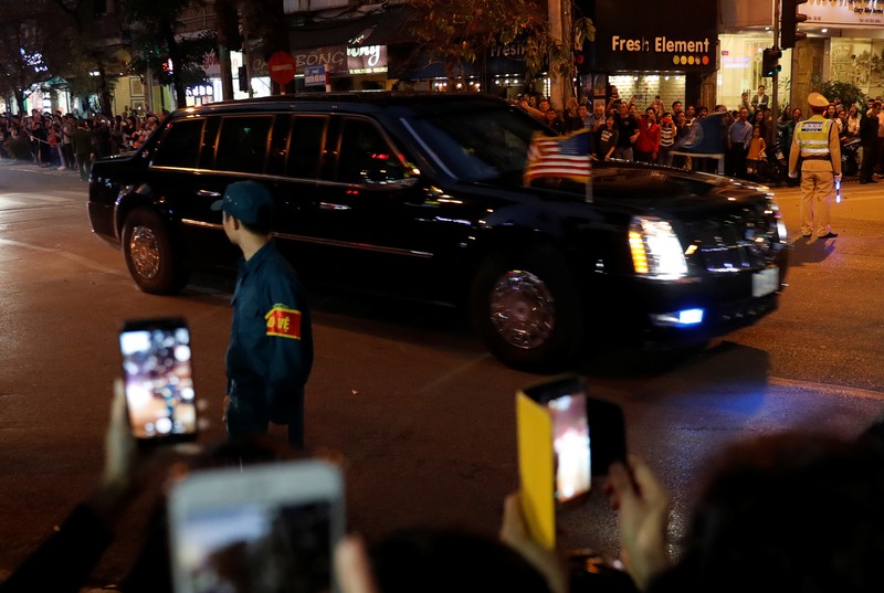 The motorcade of U.S. President Donald Trump passes bystanders on a road near the Metropole Hotel in Hanoi