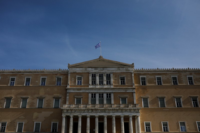 A Greek national flag flutters atop the parliament building in Athens