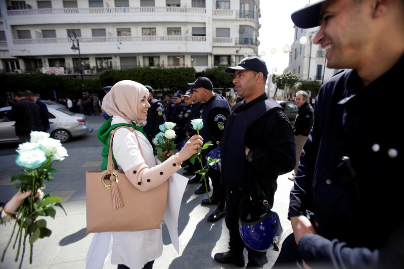 A demonstrator offers a flower to a police officer as teachers and students take part in a protest demanding immediate political change in Algiers,