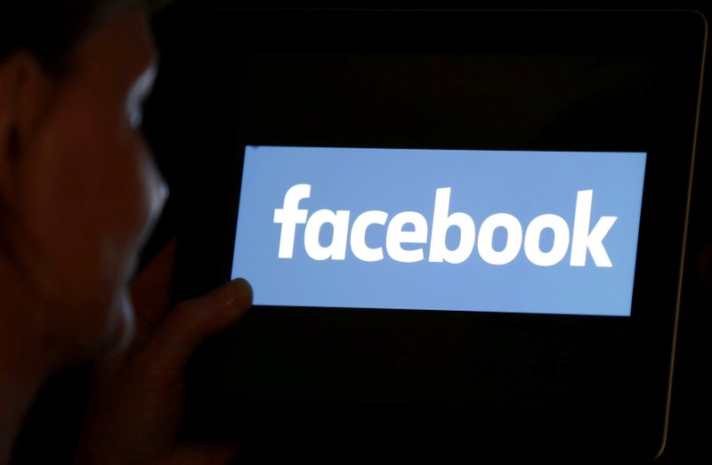 FILE PHOTO: A woman looks at the Facebook logo on an iPad in this photo illustration